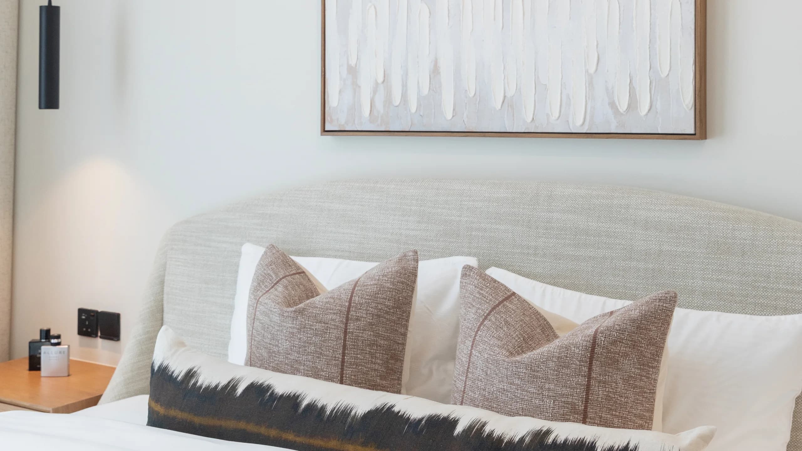 Bedroom with a soft upholstered headboard and a large abstract canvas in rose and white