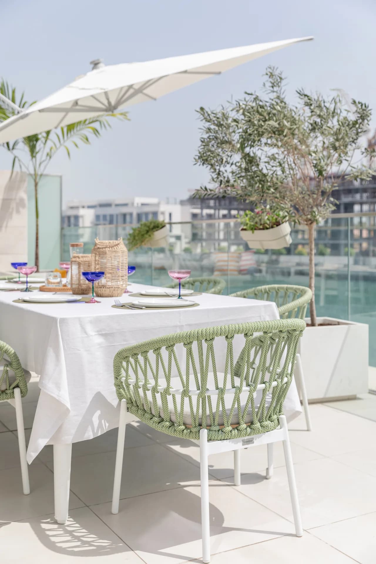 Terrace dining set with woven chairs, olive trees and a view across the marina