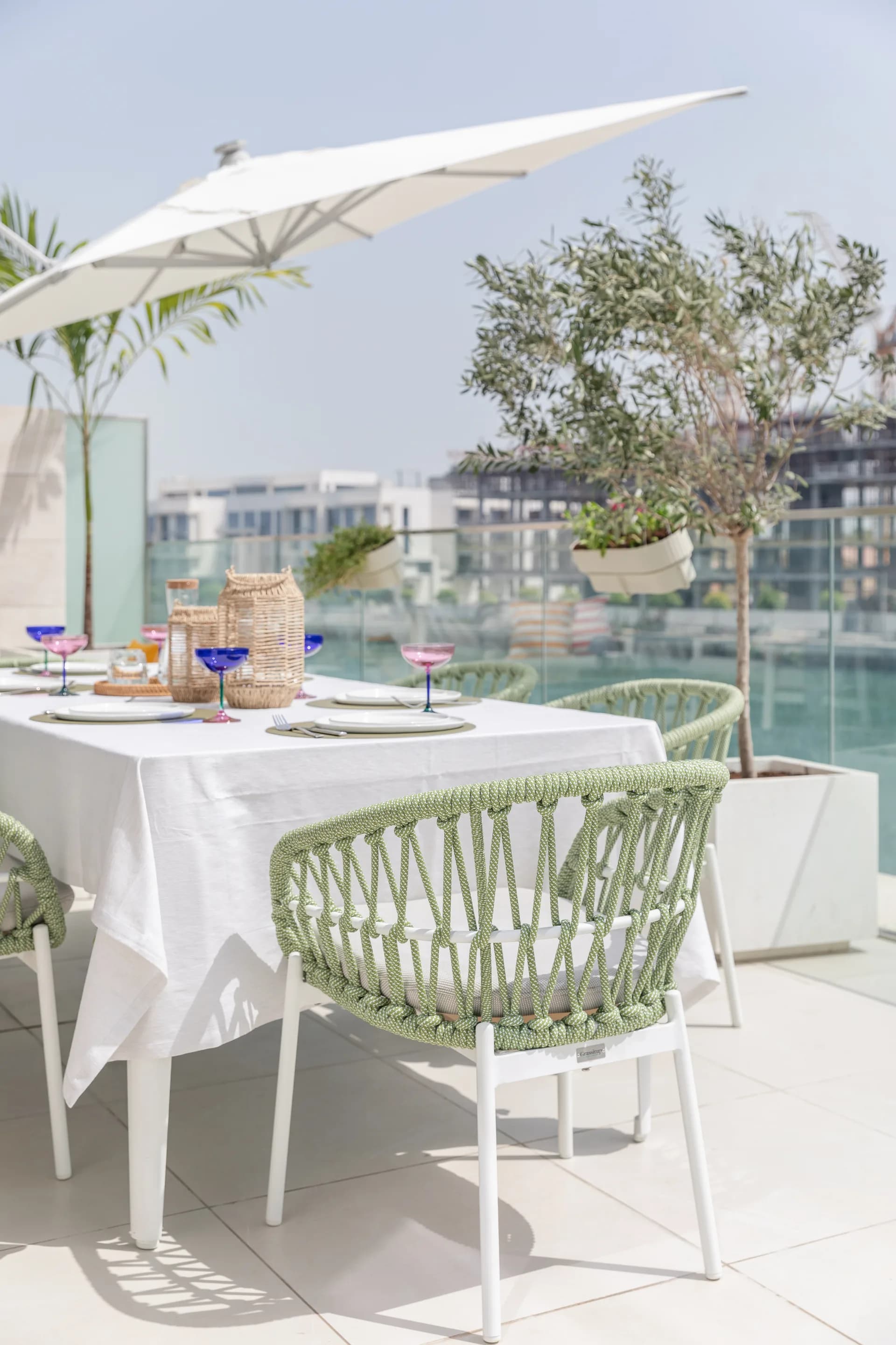 Terrace dining set with woven chairs, olive trees and a view across the marina