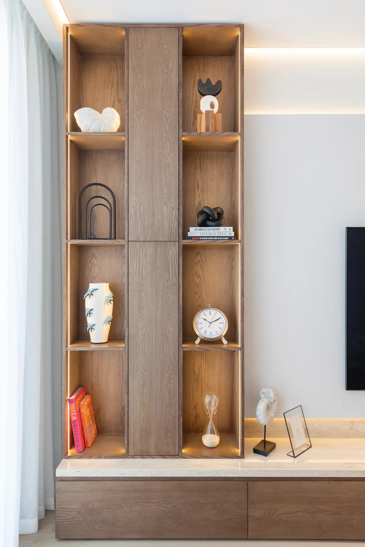 Built-in oak display shelving with sculptural objects and integrated lighting