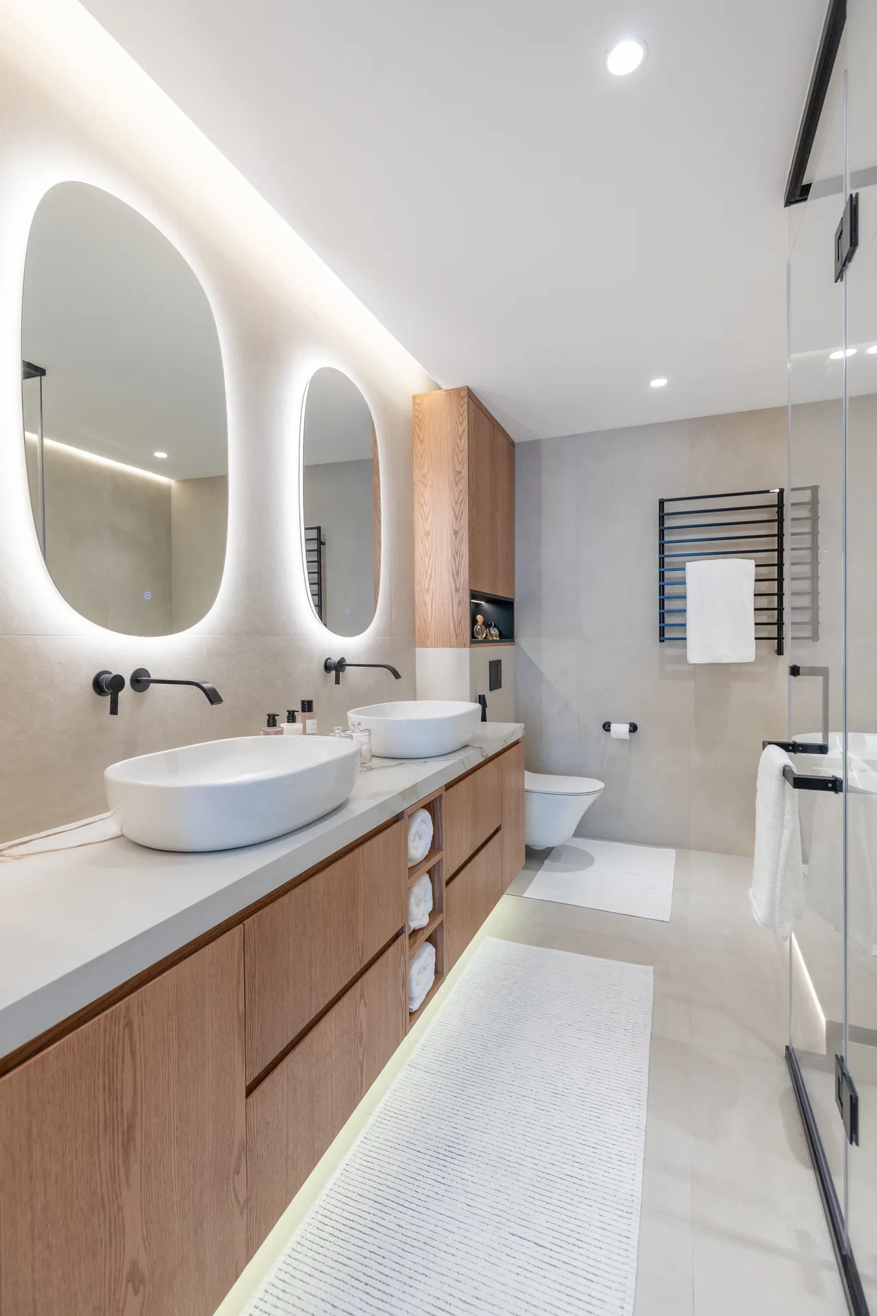Guest bathroom with twin backlit mirrors and oak vanity joinery