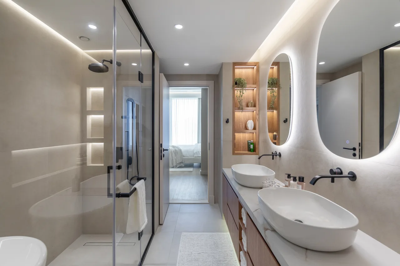 Bathroom with backlit oval mirrors, stone basins and matte black fittings