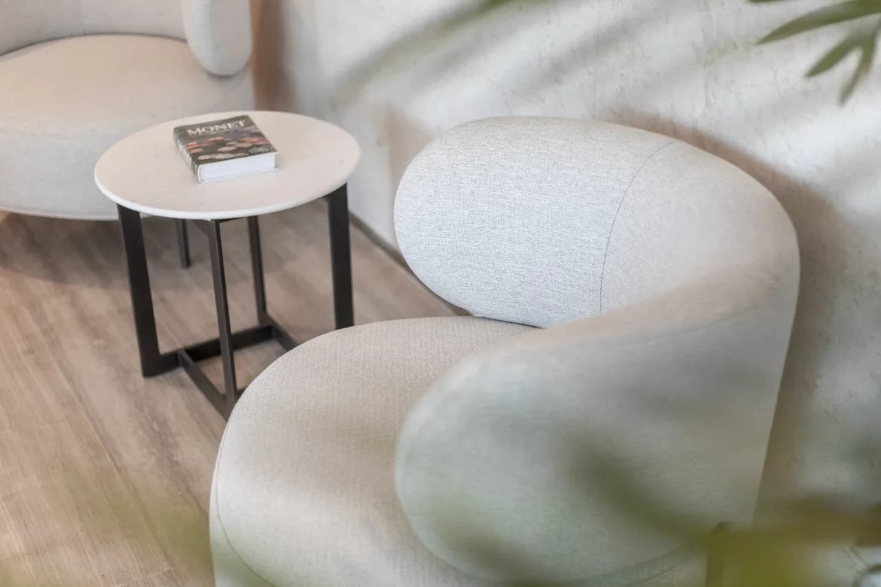 Lobby lounge with rounded pebble-form armchairs and dappled daylight on the wall